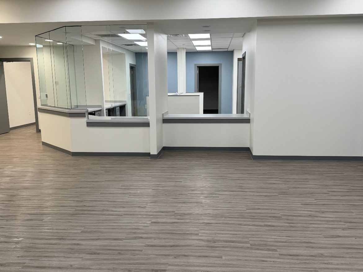 Newly built office reception area with cleaned plank flooring, reception counters and glass transaction windows after post-construction final clean