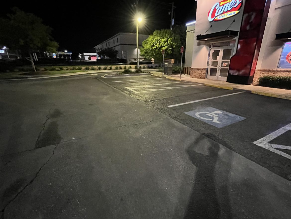 Parking lot and drive lane being washed at night at a quick-service restaurant