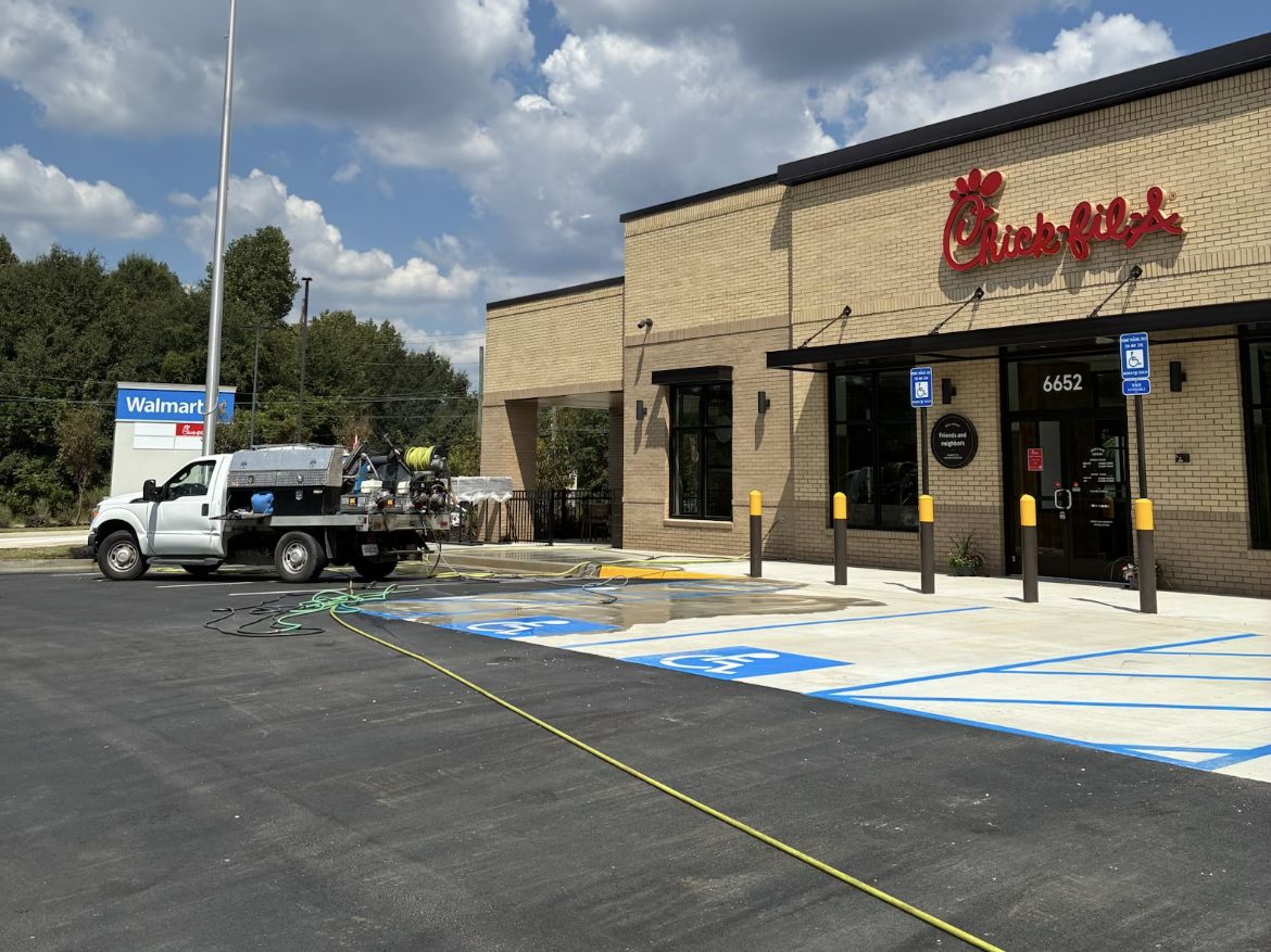 Pressure washing rig cleaning the parking area and walkway at a quick-service restaurant